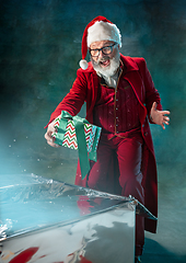 Image showing Modern stylish Santa Claus in red fashionable suit and cowboy\'s hat on dark background