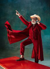 Image showing Modern stylish Santa Claus in red fashionable suit and cowboy\'s hat on dark background