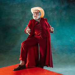 Image showing Modern stylish Santa Claus in red fashionable suit and cowboy\'s hat on dark background