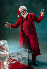 Image showing Modern stylish Santa Claus in red fashionable suit and cowboy\'s hat on dark background