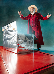 Image showing Modern stylish Santa Claus in red fashionable suit and cowboy\'s hat on dark background