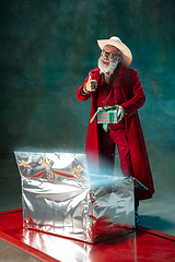 Image showing Modern stylish Santa Claus in red fashionable suit and cowboy\'s hat on dark background