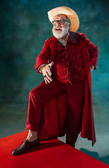 Image showing Modern stylish Santa Claus in red fashionable suit and cowboy\'s hat on dark background