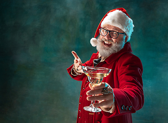 Image showing Modern stylish Santa Claus in red fashionable suit and cowboy\'s hat on dark background