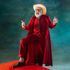 Image showing Modern stylish Santa Claus in red fashionable suit and cowboy\'s hat on dark background