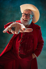 Image showing Modern stylish Santa Claus in red fashionable suit and cowboy\'s hat on dark background