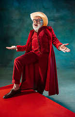 Image showing Modern stylish Santa Claus in red fashionable suit and cowboy\'s hat on dark background