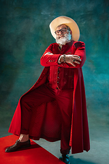 Image showing Modern stylish Santa Claus in red fashionable suit and cowboy\'s hat on dark background