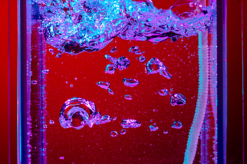 Image showing Close up view of the cold and fresh cola with bright bubbles in neon light