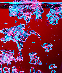 Image showing Close up view of the cold and fresh cola with bright bubbles in neon light