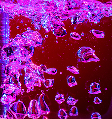 Image showing Close up view of the cold and fresh cola with bright bubbles in neon light