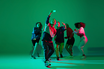 Image showing Stylish men and woman dancing hip-hop in bright clothes on gradient background at dance hall in neon light