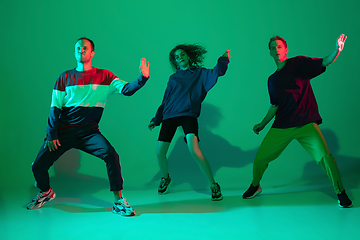 Image showing Stylish men and woman dancing hip-hop in bright clothes on gradient background at dance hall in neon light