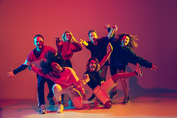 Image showing Stylish men and women dancing hip-hop in bright clothes on gradient background at dance hall in neon light