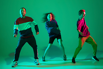 Image showing Stylish men and woman dancing hip-hop in bright clothes on gradient background at dance hall in neon light