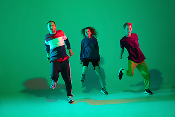 Image showing Stylish men and woman dancing hip-hop in bright clothes on gradient background at dance hall in neon light