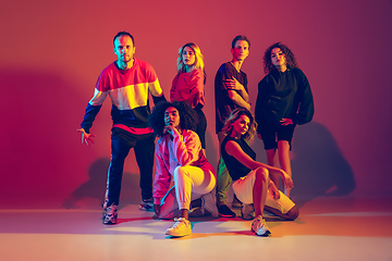 Image showing Stylish men and women dancing hip-hop in bright clothes on gradient background at dance hall in neon light