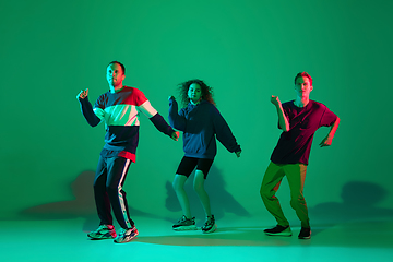 Image showing Stylish men and woman dancing hip-hop in bright clothes on gradient background at dance hall in neon light