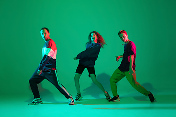 Image showing Stylish men and woman dancing hip-hop in bright clothes on gradient background at dance hall in neon light