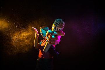 Image showing Singing with microphone. Young woman with smoke and neon light on black background. Highly tensioned, wide angle, fish eye view