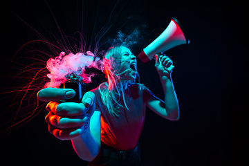 Image showing Shouting with megaphone. Young woman with smoke and neon light on black background. Highly tensioned, wide angle, fish eye view