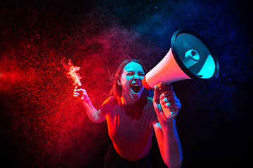 Image showing Shouting with megaphone. Young woman with smoke and neon light on black background. Highly tensioned, wide angle, fish eye view