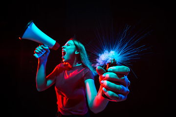 Image showing Shouting with megaphone. Young woman with smoke and neon light on black background. Highly tensioned, wide angle, fish eye view