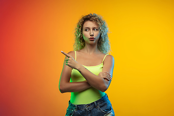 Image showing Caucasian young woman\'s portrait on gradient studio background in neon