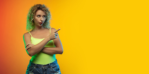 Image showing Caucasian young woman\'s portrait on gradient studio background in neon