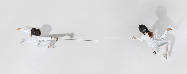 Image showing Teen girl in fencing costume with sword in hand isolated on white background, top view