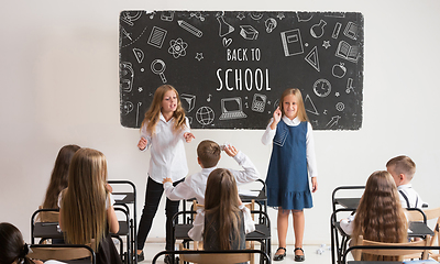 Image showing School children in classroom at lesson with worlds Back to school on classboard