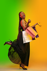 Image showing Portrait of young woman in neon light on gradient backgound. The human emotions, black friday, cyber monday, purchases, sales, finance concept.