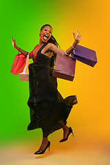 Image showing Portrait of young woman in neon light on gradient backgound. The human emotions, black friday, cyber monday, purchases, sales, finance concept.