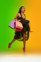 Image showing Portrait of young woman in neon light on gradient backgound. The human emotions, black friday, cyber monday, purchases, sales, finance concept.