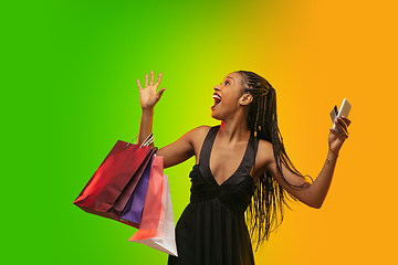 Image showing Portrait of young woman in neon light on gradient backgound. The human emotions, black friday, cyber monday, purchases, sales, finance concept.