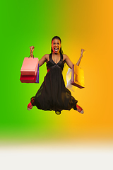 Image showing Portrait of young woman in neon light on gradient backgound. The human emotions, black friday, cyber monday, purchases, sales, finance concept.