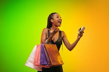 Image showing Portrait of young woman in neon light on gradient backgound. The human emotions, black friday, cyber monday, purchases, sales, finance concept.