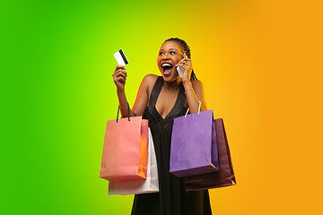 Image showing Portrait of young woman in neon light on gradient backgound. The human emotions, black friday, cyber monday, purchases, sales, finance concept.