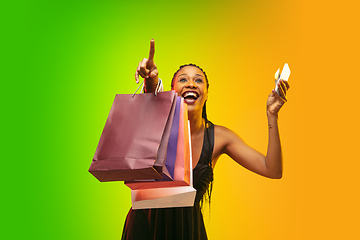 Image showing Portrait of young woman in neon light on gradient backgound. The human emotions, black friday, cyber monday, purchases, sales, finance concept.