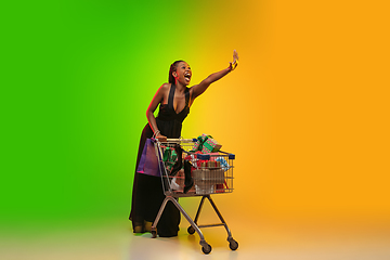 Image showing Portrait of young woman in neon light on gradient backgound. The human emotions, black friday, cyber monday, purchases, sales, finance concept.