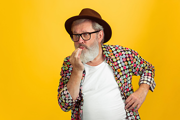 Image showing Senior hipster man wearing eyeglasses posing on yellow background. Tech and joyful elderly lifestyle concept