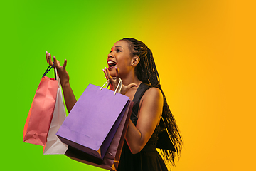 Image showing Portrait of young woman in neon light on gradient backgound. The human emotions, black friday, cyber monday, purchases, sales, finance concept.