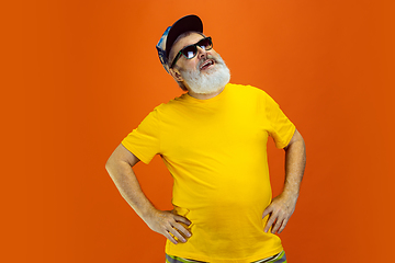 Image showing Senior hipster man wearing eyeglasses posing on orange background. Tech and joyful elderly lifestyle concept