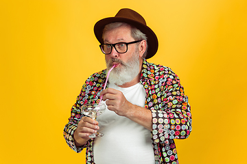 Image showing Senior hipster man wearing eyeglasses posing on yellow background. Tech and joyful elderly lifestyle concept