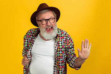 Image showing Senior hipster man wearing eyeglasses posing on yellow background. Tech and joyful elderly lifestyle concept