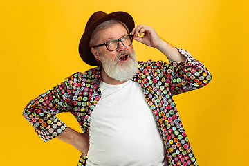 Image showing Senior hipster man wearing eyeglasses posing on yellow background. Tech and joyful elderly lifestyle concept