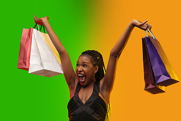 Image showing Portrait of young woman in neon light on gradient backgound. The human emotions, black friday, cyber monday, purchases, sales, finance concept.