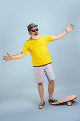 Image showing Senior hipster man wearing eyeglasses posing on light blue background. Tech and joyful elderly lifestyle concept