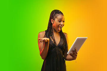 Image showing Portrait of young woman in neon light on gradient backgound. The human emotions, black friday, cyber monday, purchases, sales, finance concept.