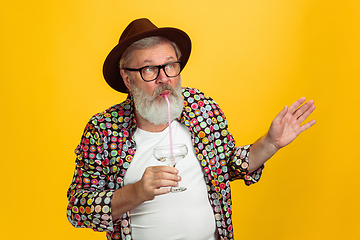 Image showing Senior hipster man wearing eyeglasses posing on yellow background. Tech and joyful elderly lifestyle concept